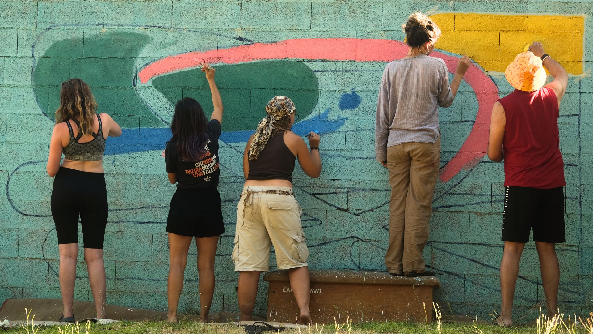 Artists painting a large outdoor mural together
